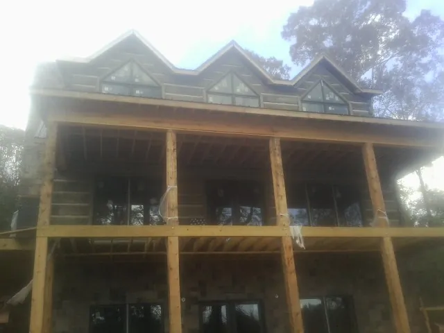 Dormers and porch framing on a large log home under construction — Roof Coating work by our crew in Russell